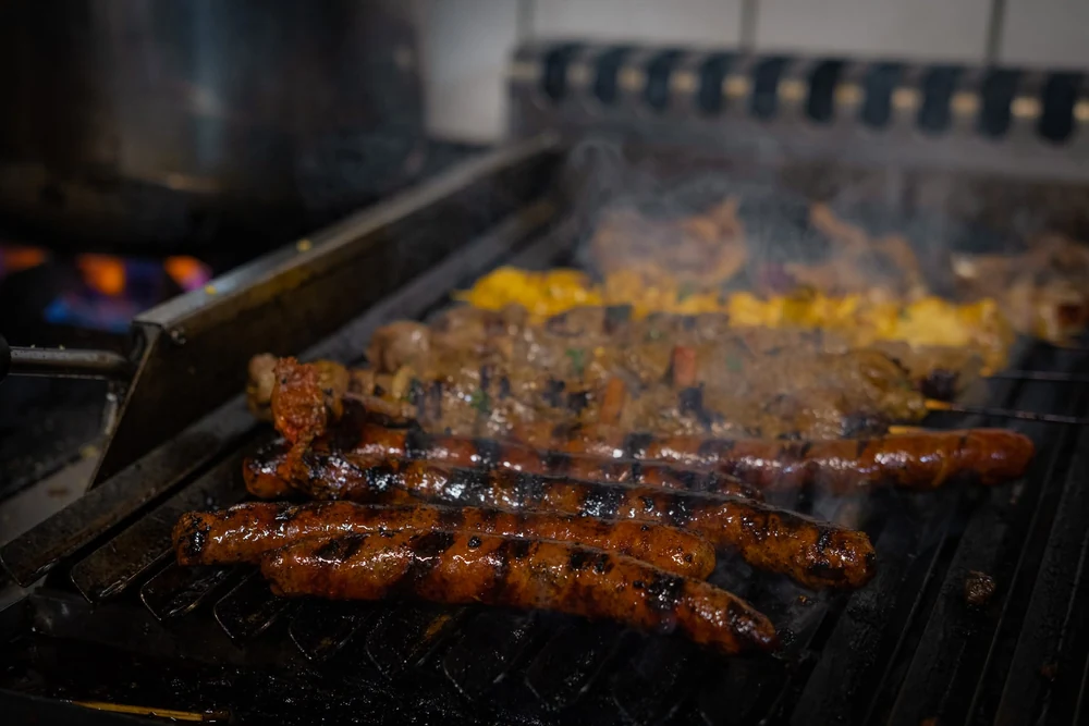 Viandes sur une grille de cuisson, entourées de fumée.