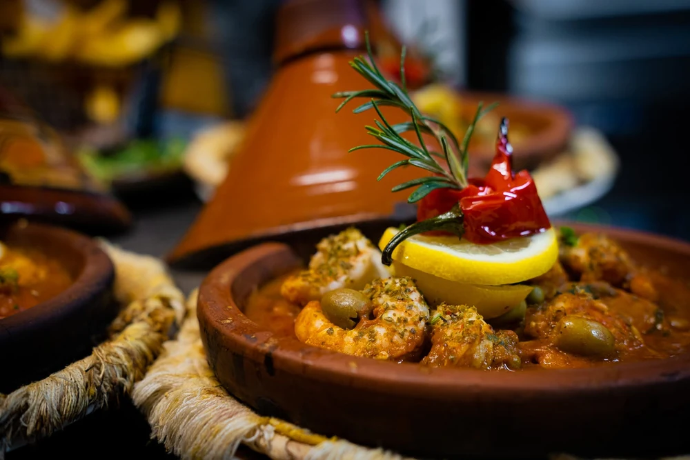 Tajine garni, avec son couvercle en terre cuite en arrière-plan.