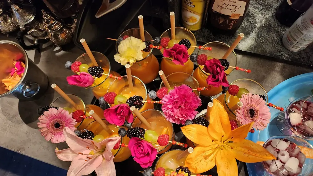 Assortiment de petites verrines colorées, garnies de fleurs et de brochettes.